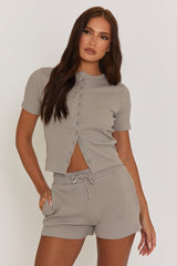 A model wearing a dove grey rib button front top with short sleeves and matching shorts, both made of rib knit fabric.
